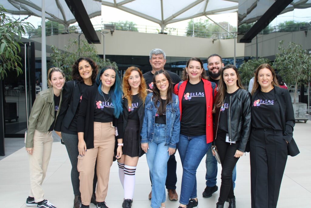 Membros do projeto posando para foto. A equipe se encontra em uma área externa da universidade de Lima, onde é possível ver um teto de vidro.