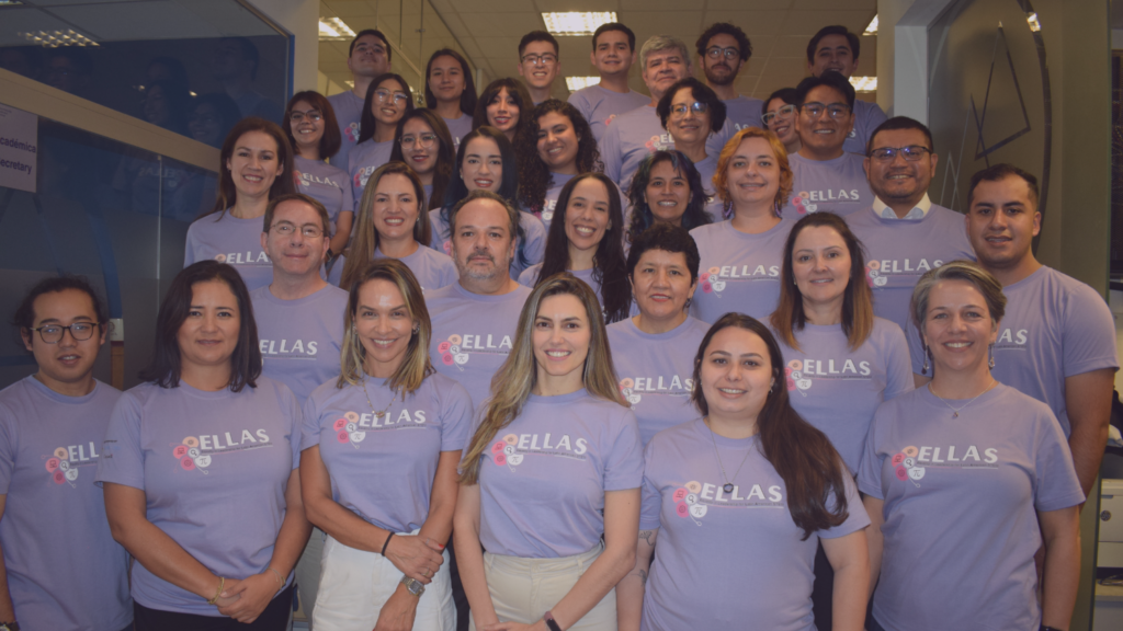 Membros do projeto ELLAS reunidos e posando para a foto enfileirados em uma escada. Todos estão usando uma camisa preta com a logo do projeto ELLAS centralizada ao meio da camisa